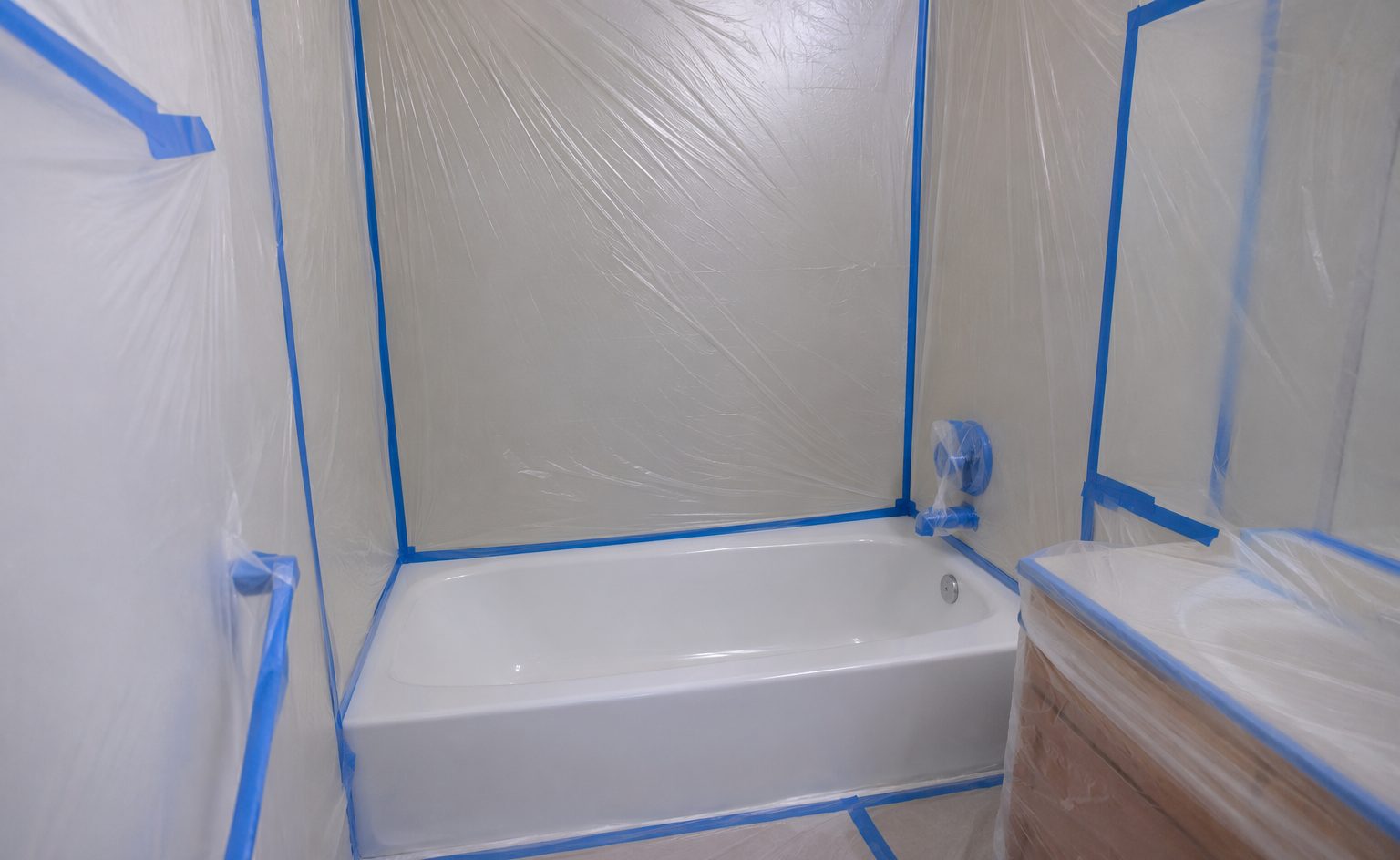 Bathroom masked and protected mid-reglazing with the tub prepared for coating