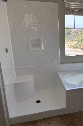 Completed senior access conversion: white walk-in shower base with a built-in corner seat beside the refinished tub deck
